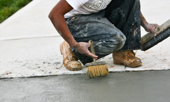 Man cleaning the edges of freshly laid asphalt